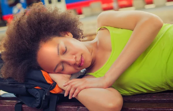 Closeup of female backpacker tourist napping on a bench