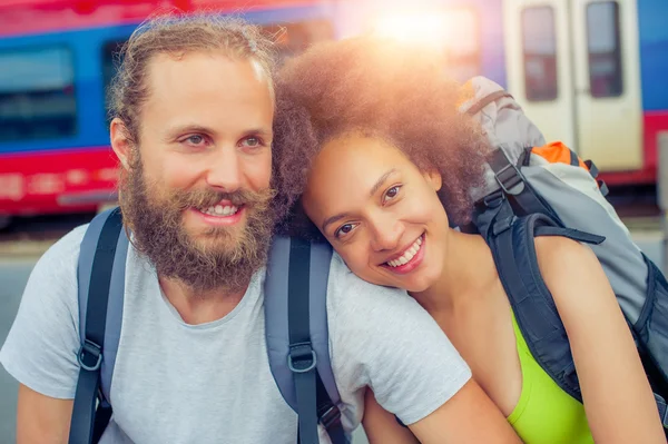 Счастливая молодая и красивая пара туристов, сидящих у железной дороги — стоковое фото