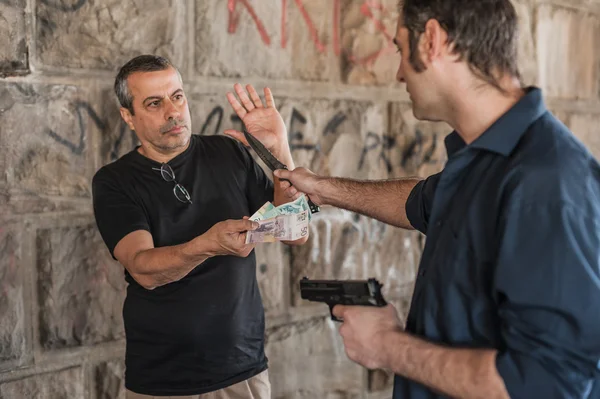 Robber with a gun and knife taking money from victim — Stock Photo, Image