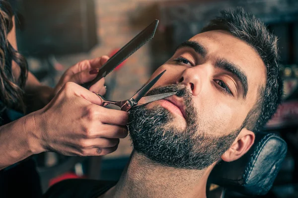 Barber skæg klippe en klients skæg med klippere - Stock-foto