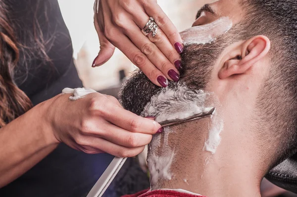 Kvinde barber barbering en klient - Stock-foto