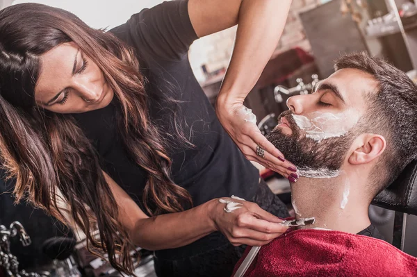 Kvinde barber barbering en klient - Stock-foto