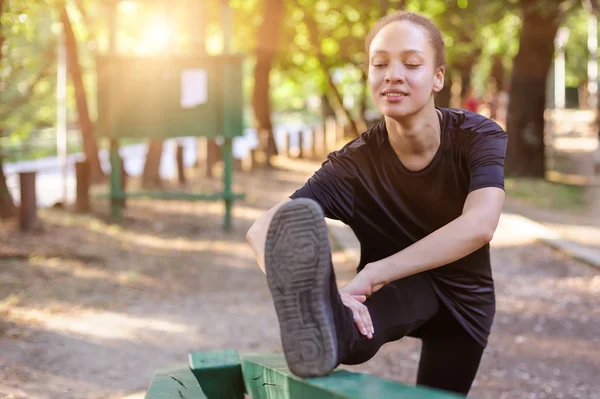Training im Freien. fitte junge Frau streckt ihre Beine. — Stockfoto