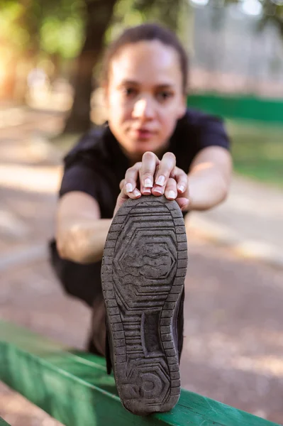 Training im Freien. fitte junge Frau streckt ihre Beine. — Stockfoto