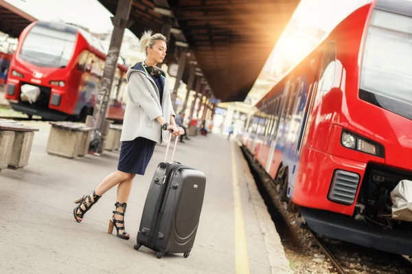 Элегантная женщина с чемоданом позирует на железнодорожном вокзале — стоковое фото