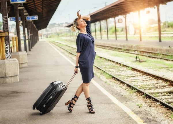 Элегантная женщина с чемоданом позирует на железнодорожном вокзале — стоковое фото