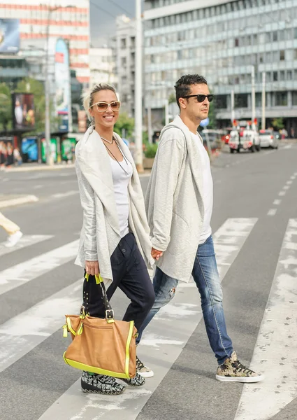 Pareja de moda cruzando la carretera en el cruce de cebra peatonal —  Fotos de Stock