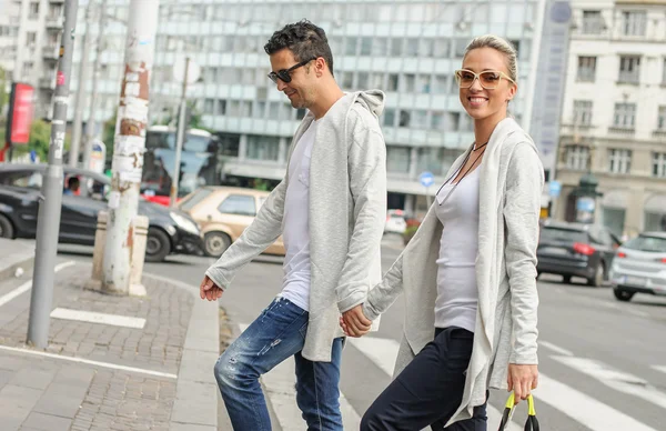 Fashionable couple crossing road at pedestrian zebra crossing — Stock Photo, Image