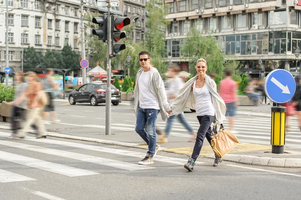Pareja de moda cruzando la carretera en el cruce de cebra peatonal —  Fotos de Stock