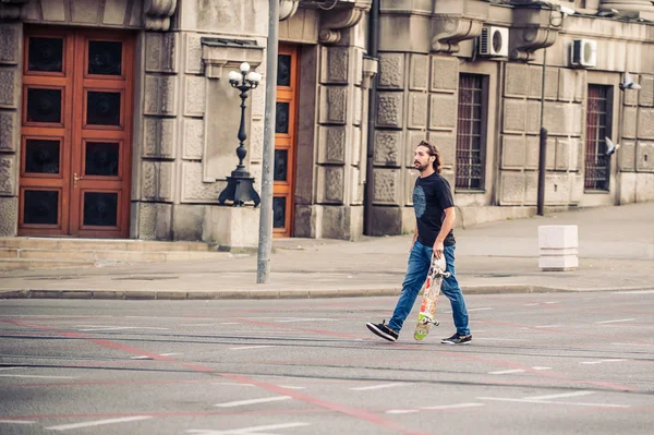 Skateboarder cruzar la carretera en las calles de la ciudad capital —  Fotos de Stock