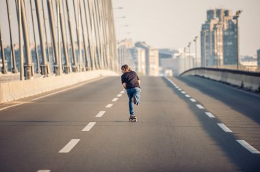 Skateboarder riding a skate over a city road bridge clipart