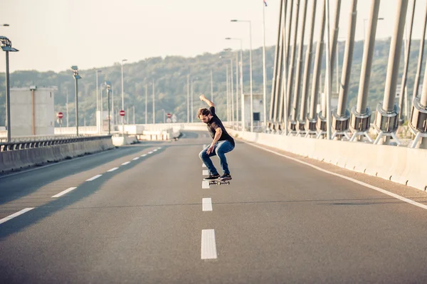 Skateboarder montando un patín y haciendo saltos en el puente de carretera —  Fotos de Stock