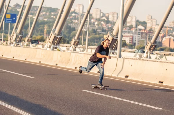 Skateboarder riding a skate over a city road bridge — Stock Photo, Image