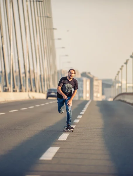 Skateboarder montando um skate sobre uma ponte rodoviária da cidade — Fotografia de Stock