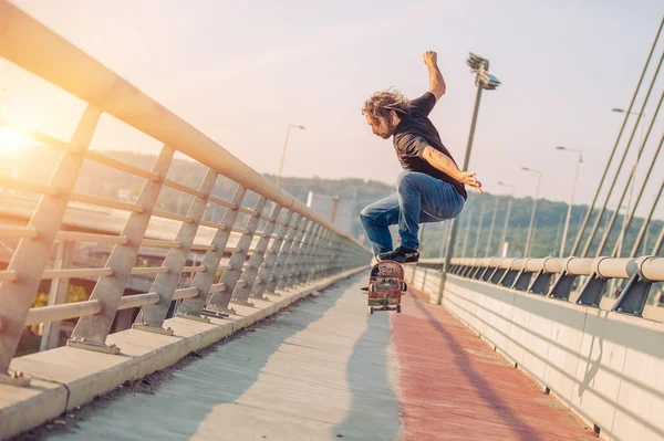 Skateboarder patina e fazendo saltos sobre uma ponte da cidade — Fotografia de Stock