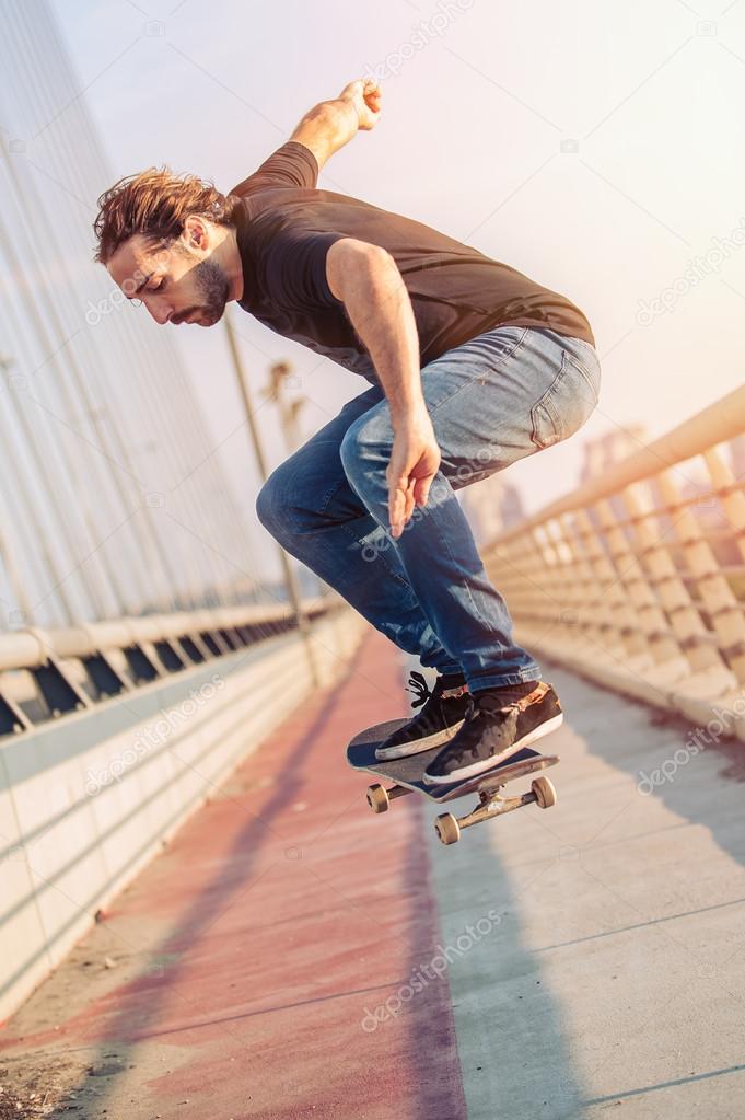 Skateboarder skates and doing jumps over a city bridge