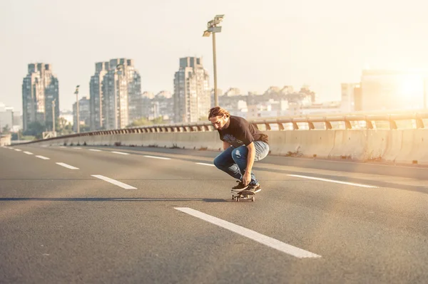 Skateboarder montando um skate sobre uma ponte rodoviária da cidade — Fotografia de Stock