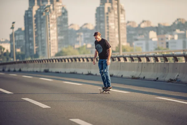 Skateboarder montando um skate sobre uma ponte rodoviária da cidade — Fotografia de Stock