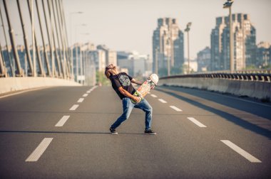 Happy skateboarder on the bridge playing guitar on his skate 