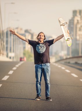Happy skateboarder standing on the road bridge 