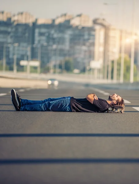 Сумасшедший скейтбордист лежит посреди автодорожного моста — стоковое фото