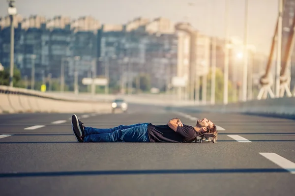 Verrückter Skateboarder liegt mitten auf einer Autobahnbrücke — Stockfoto