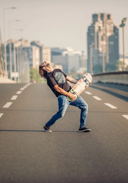 Feliz skatista na ponte tocando guitarra em seu skate — Fotografia de Stock