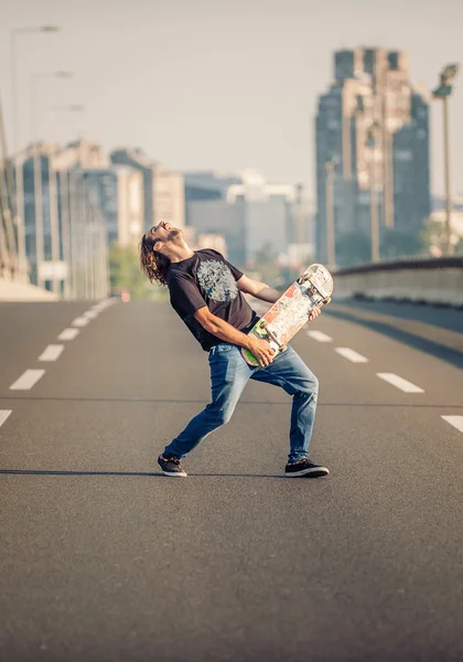 Happy skateboarder on the bridge playing guitar on his skate 