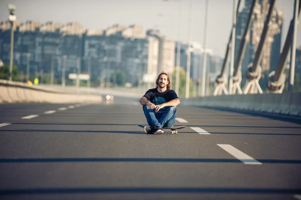 Skateboarder κάθεται στο skateboard του στη γέφυρα της εθνικής οδού — Φωτογραφία Αρχείου