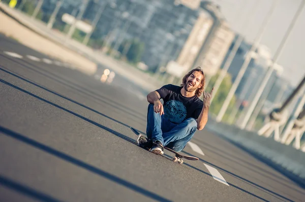 Skateboarder zittend op zijn skateboard op de brug van de snelweg — Stockfoto
