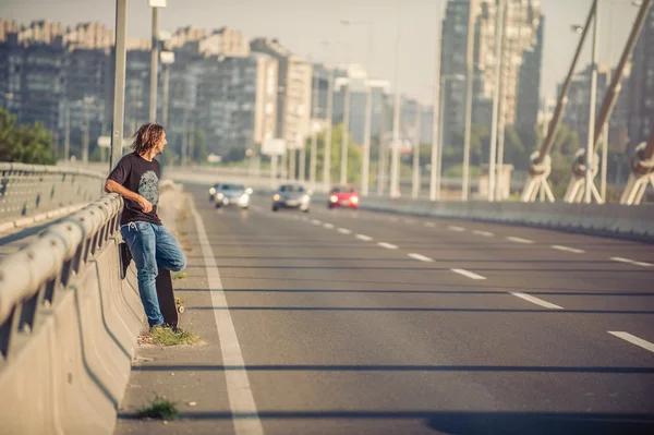 Скейтбордист, що стоїть на мосту, спирається на паркан і дивиться — стокове фото