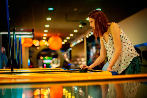 Jonge vrouw spelen van een spel van air hockey — Stockfoto