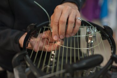 Close up of tennis stringer hands doing racket stringing clipart