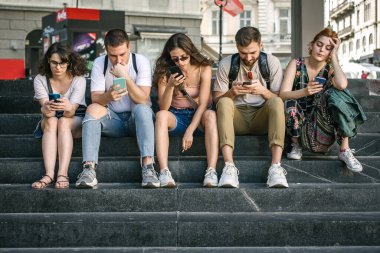 Akıllı telefonları birlikte kullanan bir grup arkadaş. Gençler yeni teknoloji eğilimlerine bağımlı. Gençlik, yeni nesil internet arkadaşlık kavramı. Duygusal izolasyon ve küçümseme