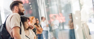 Alışveriş merkezindeki bir grup insan bir butiğin vitrininde yeni moda giysiler arıyor. Dükkan satışları. Kara Cuma konsepti