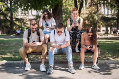 Akıllı telefonları birlikte kullanan bir grup arkadaş. Gençler yeni teknoloji eğilimlerine bağımlı. Gençlik, yeni nesil internet arkadaşlık kavramı. Duygusal izolasyon ve küçümseme
