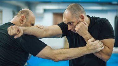 Dövüş antrenmanı ve dövüş tekniği gösterisi. Dojo salonunda saldırgana karşı. Dövüş sanatları pratiği