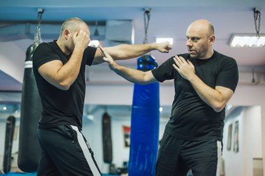 Dövüş antrenmanı ve dövüş tekniği gösterisi. Dojo salonunda saldırgana karşı. Dövüş sanatları pratiği