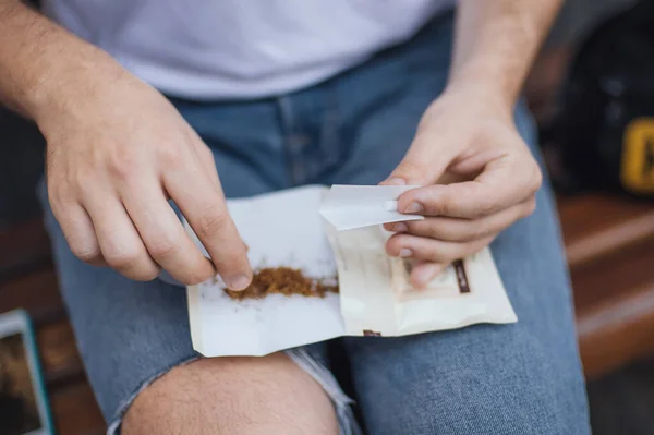 Jovem Viciado Sentado Banco Parque Cigarro Rolando Preparando Para Fumar — Fotografia de Stock