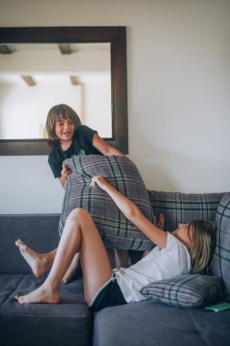 Yastıklarla oynuyorlar. Evde iki mutlu çocuk. Erkek ve kız kardeş birlikte. Yastık savaşı. Aile kavramı