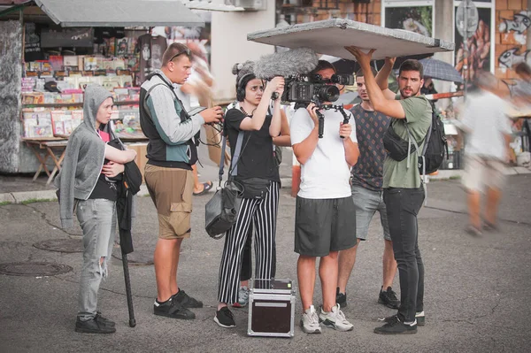 Behind the scenes. Film crew team shooting movie scene on outdoor location. Group filmmaking set production