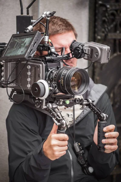 Behind the scene. Cameraman shooting the film scene with his camera on outdoor set. Photography director in movie filmmaking action