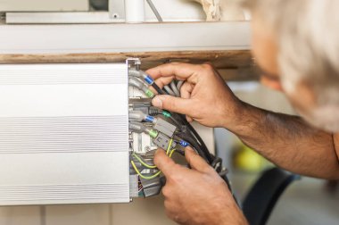 Elektrik mühendisinin kapağı elektrik kablolarıyla çalışıyor. Kurulum denetimi. Elektrik ekipmanları