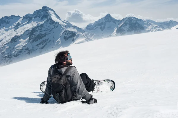 Snowboarder sentarse en la cima de la montaña — Foto de Stock