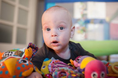 Meraklı bir bebek, güneşli bir oyun odasında çeşitli canlı oyuncaklarla çevrili oturur. Yeni dokular ve renkler keşfederken gözleri merakla ve heyecanla açılır..
