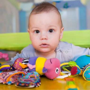 Meraklı bir bebek göbeğinde yatıyor. Oyuncak gökkuşağıyla çevrili. Neşeli oyun odasındaki dokuları ve renkleri keşfetmek için sabırsızlıkla uzanıyor..
