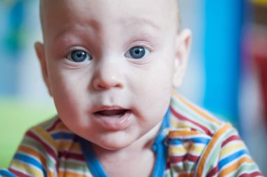 Yumuşak, renkli bir ortamda, meraklı bir bebek parlak mavi gözlerle masumiyet ve merakın özünü yakalıyor. Canlı detaylar büyüleyici bir portre oluşturur..