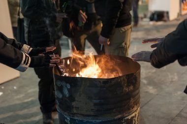 Evsiz adam ellerini ateşin yanında Isınma