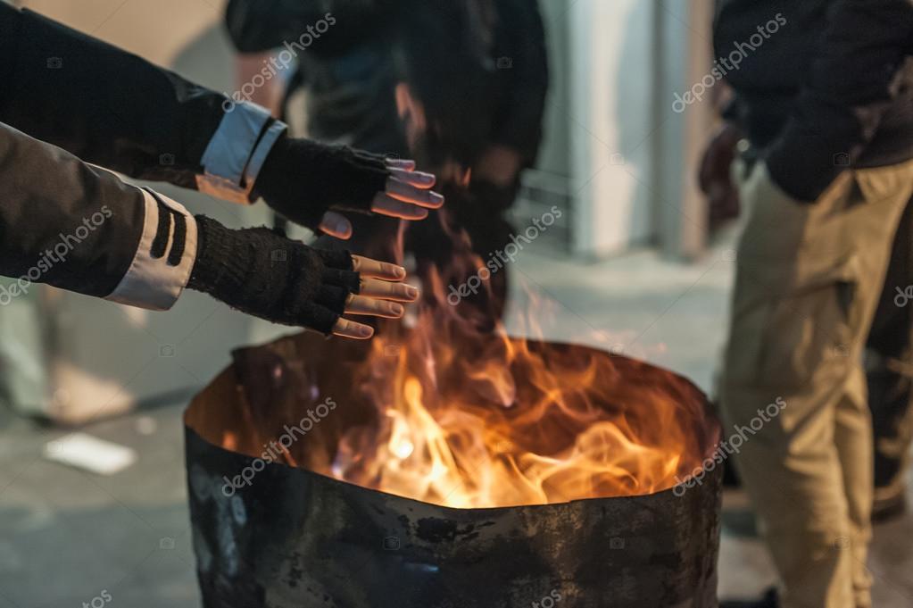 Un SDF se réchauffe les mains par le feu image libre de droit par