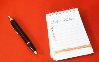Kırmızı arkaplanda günlük not defteri ve kalem planı